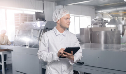 Worker control quality of sweets candy with computer tablet. Concept banner modern food industry,...