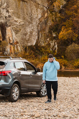 man at the rocky beach in mountain river near car