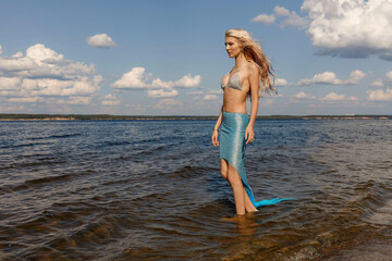 a girl in a mermaid dress on the riverbank, taken on a sunny day