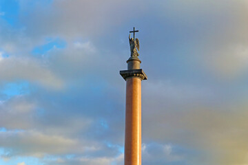 Alexander Column near the Winter Palace in Saint Petersburg, Russia. A monument with a sculpture of an Angel holding a cross against a blue sky with clouds