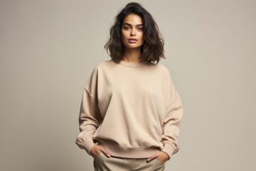 Obraz premium Isolated Portrait of a Fictional Female Model Wearing a Large Oversized Beige Colored Sweatshirt on a Plain Blank Background. Generative AI.