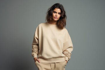 Isolated Portrait of a Fictional Female Model Wearing a Large Oversized Beige Colored Sweatshirt on a Plain Blank Background. Generative AI.