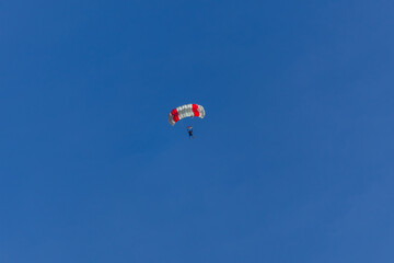 Parachutist silhouette against clear blue sky. Sport, hobby background