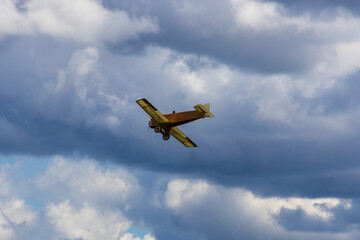 Fototapeta na wymiar Old historic biplane fly on cloudy sky from side