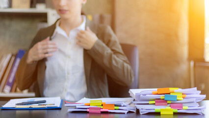 Businesswoman hands working on stacks of paper documents to search and review documents piled on...