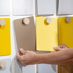 Designer hands compare colorful laminate sheets on material swatch wall display in material...