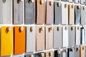 Set of colorful wooden laminate sheets hanging on material swatch wall display in material library....