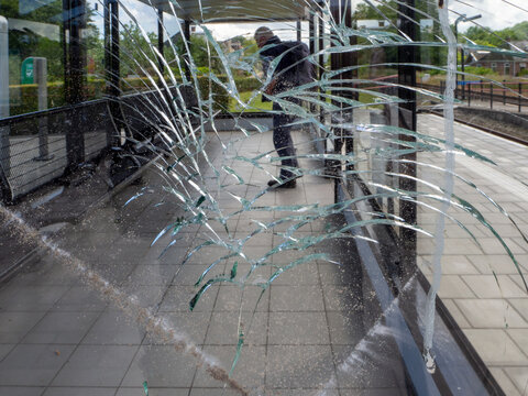 Man at trainstation in front of a broken window