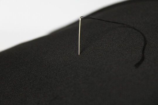 Black thread and needle on fabric