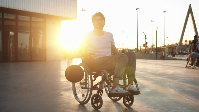 A man in a wheelchair hitting the basketball on the playground at sunset