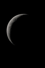 Crescent moon photographed with a telescope, where you can see the craters and the lunar surface, it will soon be a moon landing site