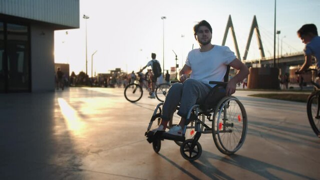 A man in a wheelchair checking his phone and looking around in the park then riding off the frame