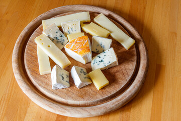 Cheese platter with different kinds of cheese on wooden table