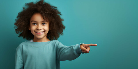 a child pointing to a plain blue background, happiness, joy, fashion