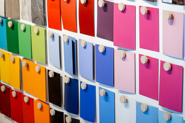 Set of colorful wooden laminate sheets hanging on material swatch wall display in material library....