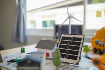 On desk of engineers lay model of house And solar panels to use in planning installation of solar...