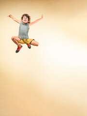 Boy with a straw hat jumping as high as he can.