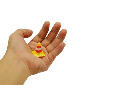 A hand holding a traffic cone isolated on white background with clipping path, abstract traffic and warning concept