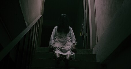 Horror scene of a mysterious Scary Asian ghost woman creepy have hair covering the face sitting on...