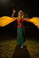 a traditional Indonesian dancer dances with a yellow scarf that floats in the air
