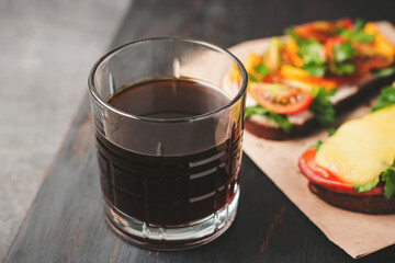 Fototapeta na wymiar Breakfast with glass of americano coffee and sandwiches on a dark wooden board