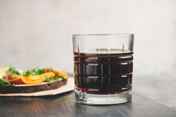 Breakfast with glass of americano coffee and sandwiches on a dark wooden board