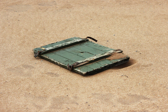 Summer beach backdrop with lid from wooden ammunition box after high tide and low tide.