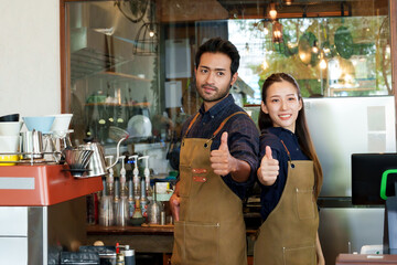 Beautiful Asian women and Asian men of various nationalities. They stood with their thumbs up at  bar counter. to take pictures to promote coffee shops that are small businesses minimalist style shop