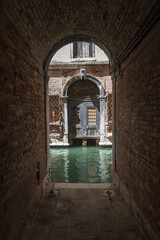 Fototapeta na wymiar Un sotoportego si affaccia su un canale e un palazzo storico a Venezia
