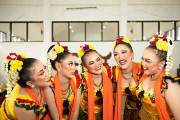 a group of traditional Javanese dancers laughing together with ridiculous faces and full of joy while on stage
