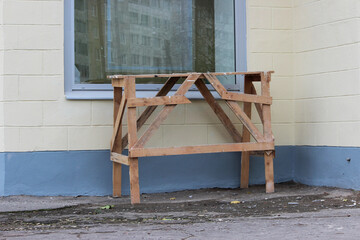 Handmade work bench on a construction site against a beige and blue plastered walls and window.