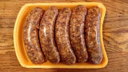 Five links of uncooked Italian sausage in plastic packaging tray