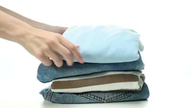 Woman female hand folding things clothes jeans, shirts, sweaters on white background isolation