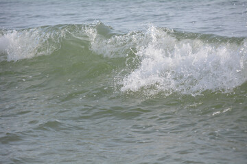 Ocean waves crashing on sandy beach. Sea waves breaking on shore. Nature splash on summer day. Sea wave crashing on beach. Summer holidays concept. Splashing sea water with foam.