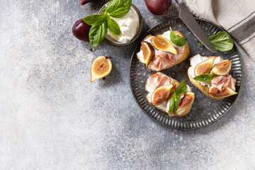 Toast or bruschetta with bacon and figs, cream cheese and honey on a gray stone background. Italian appetizer recipe. View from above. Copy space.