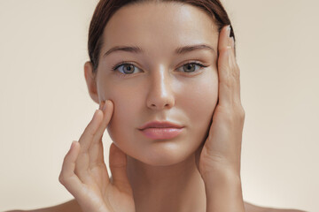 Anti-aging treatment and plastic surgery concept. Beautiful young woman with a hand on her cheek...