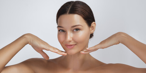 Happy beautiful young adult woman touching her perfect face with healthy shiny skin, hands on chin....