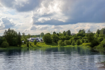 houses on the shore of a pond, clouds above the ground, summer evening