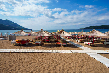 Summer sea coast in the resort town, beach with sun loungers and umbrellas, blue sunny sky, background of travel during vacation