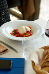 Lunchtime Delight: Bread, Smartphone, and Pasta with Burrata on the Table