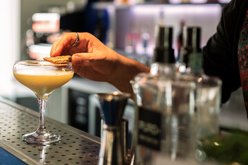 Crafting Perfection: Bartender's Hand Perfecting a Goblet Cocktail on Blue Glossy Counter