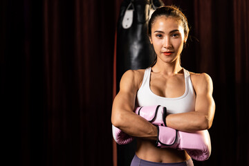 Asian female Muay Thai boxer punch fist in front of camera in ready to fight stance posing at gym...