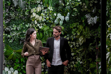 Businessman and casual businesswoman talking outdoors. Two young multicultural coworkers watching...