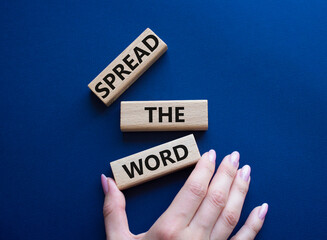 Spread the Word symbol. Concept wordsSpread the Word on wooden blocks. Beautiful deep blue background. Businessman hand. Business and Spread the Word concept. Copy space.