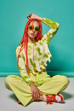 Trendy woman in stylish outfit sitting with legs crossed