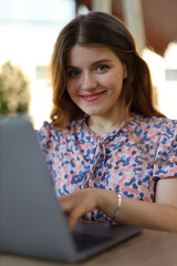 A happy and successful businesswoman working outdoors, using her laptop and mobile devices to manage her business with a smile.