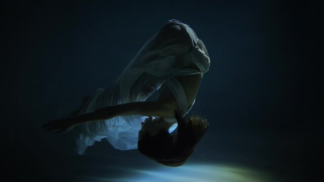 Slow motion plunging girl to fall under water. Woman dives in the pool. Girl swimming under water in basin.