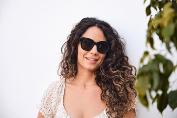 Young and stylish 26 year old beautiful girl with brown hair posing smiling in front of a white...