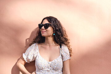 Young and stylish: 26-year-old brown-haired beauty posing in front of a light brown wall