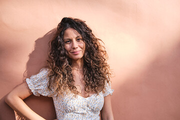 Young and stylish: 26-year-old brown-haired beauty posing in front of a light brown wall